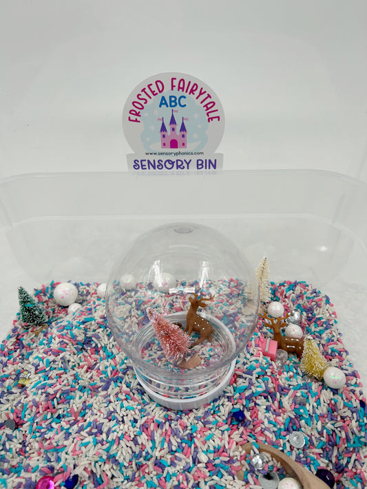 Frosted Fairytale ABC Sensory Bin label on the lid. Clear container with pastel sensory rice including a pink magnetic wand with a pink bow, metal uppercase letters and a laminated letter matching mat, on a white background.